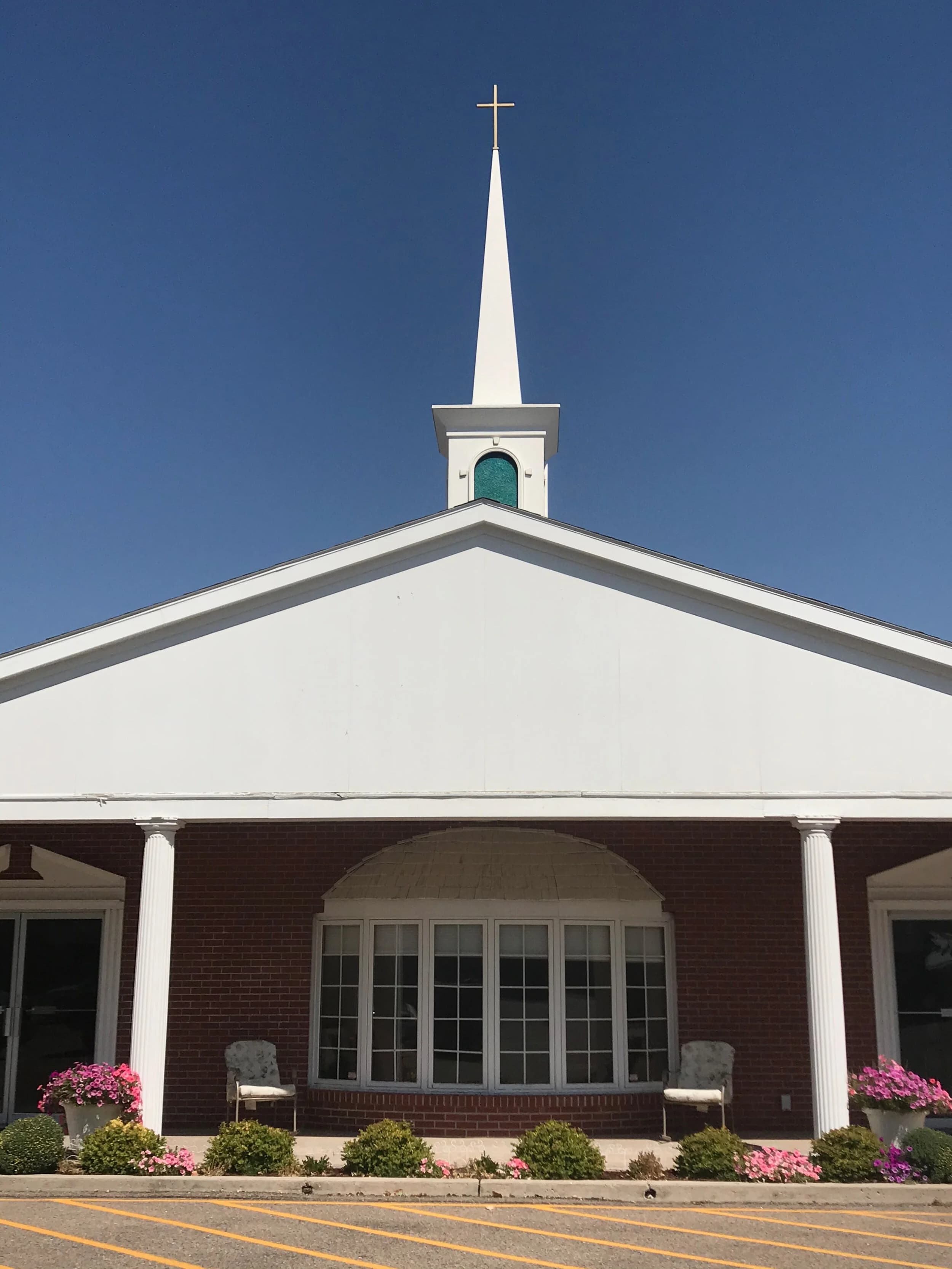 The white steeple and gold cross of Faith Baptist Church against the Wyoming sky